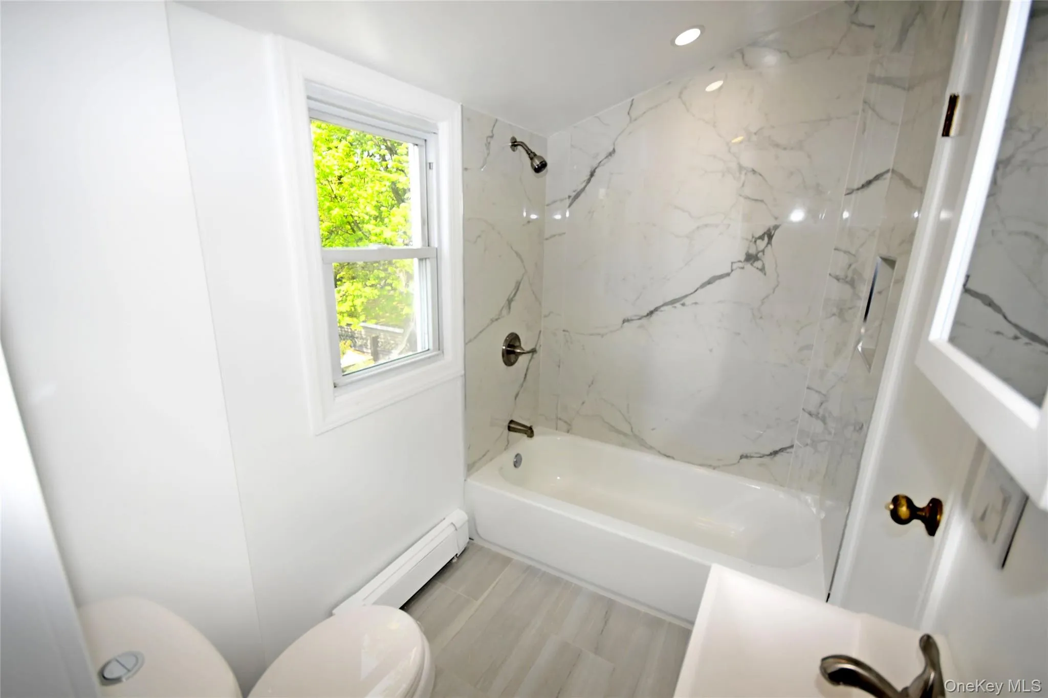 Bathroom featuring baseboard heating, toilet, shower / tub combination, and recessed lighting Bathroom featuring baseboard heating, toilet, shower / tub combination, and recessed lighting