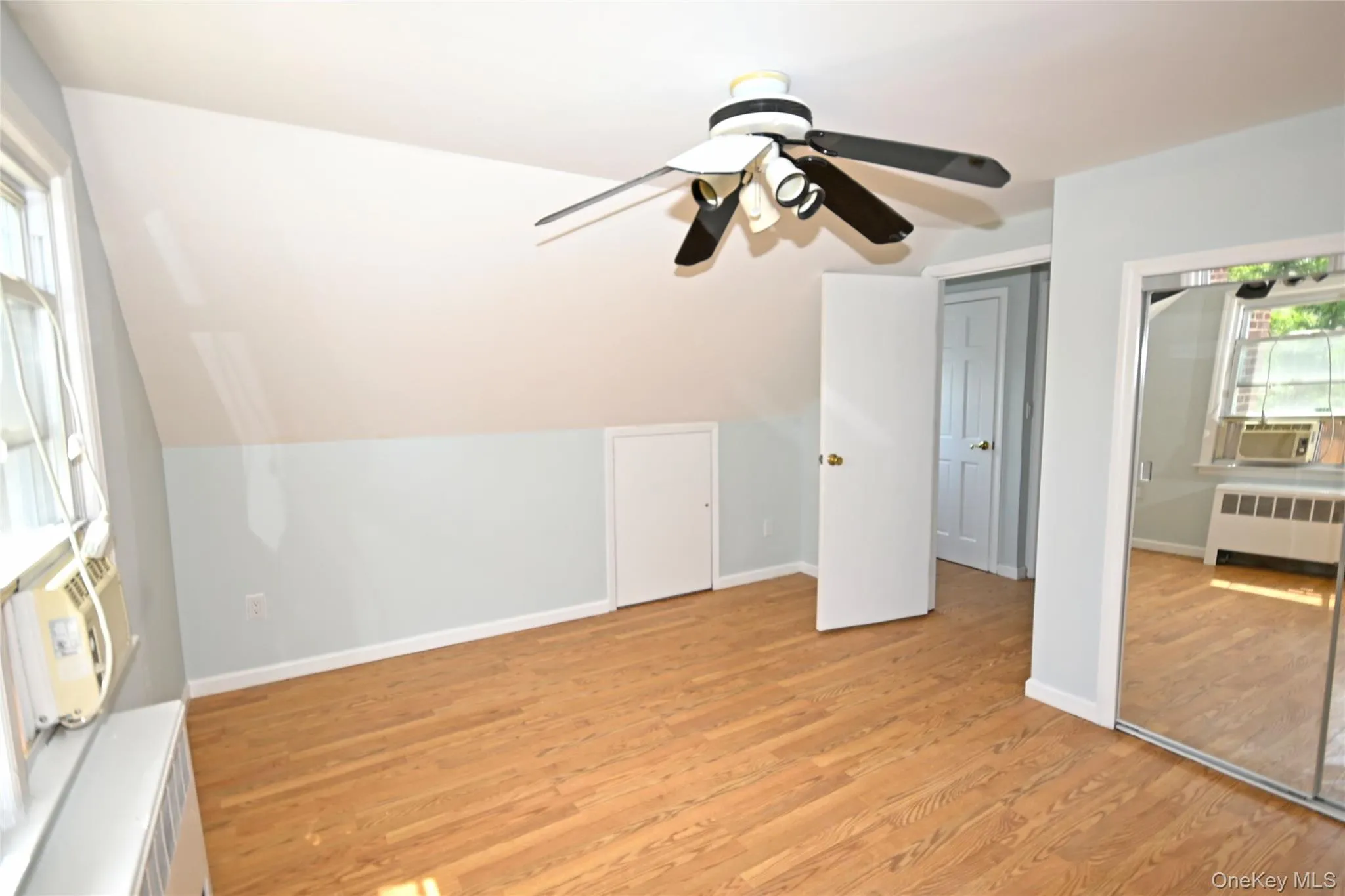 Bonus room featuring radiator heating unit, light wood-type flooring, ceiling fan, lofted ceiling, and baseboards Bonus room featuring radiator heating unit, light wood-type flooring, ceiling fan, lofted ceiling, and baseboards