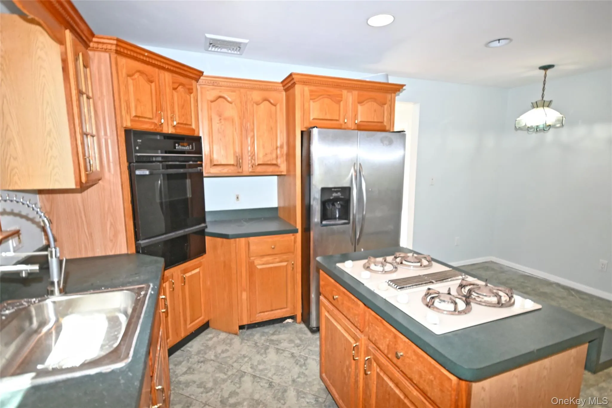Kitchen featuring black oven, a warming drawer, stovetop with downdraft, and dark countertops Kitchen featuring black oven, a warming drawer, stovetop with downdraft, and dark countertops