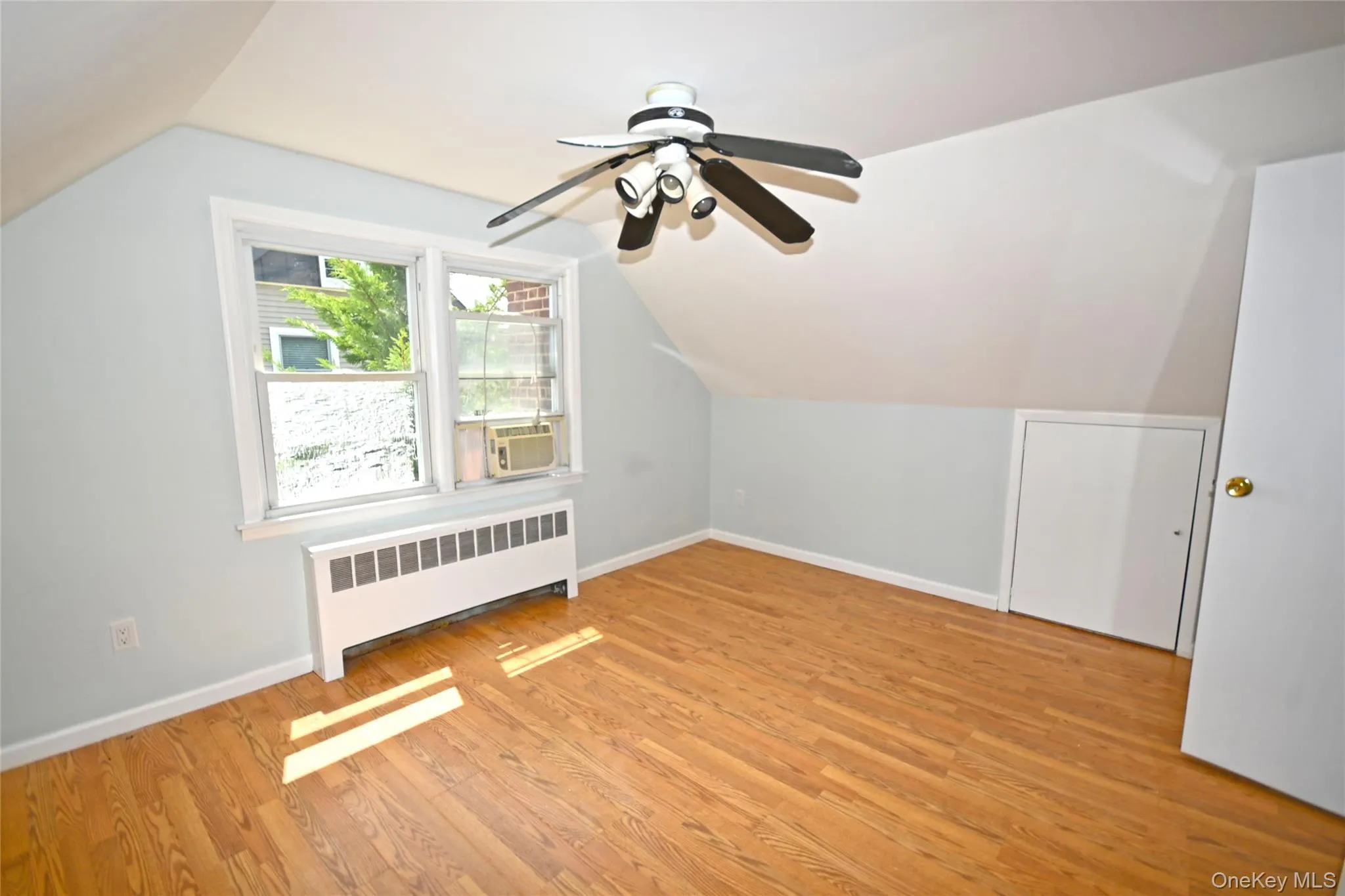 Additional living space featuring radiator heating unit, lofted ceiling, ceiling fan, baseboards, and light wood-type flooring Additional living space featuring radiator heating unit, lofted ceiling, ceiling fan, baseboards, and light wood-type flooring