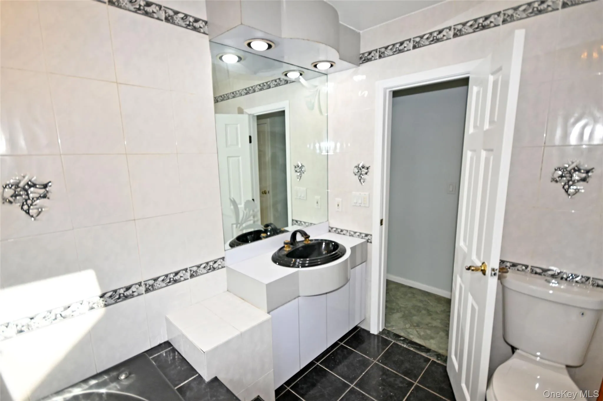 Bathroom featuring tile walls, toilet, tile patterned flooring, and vanity Bathroom featuring tile walls, toilet, tile patterned flooring, and vanity