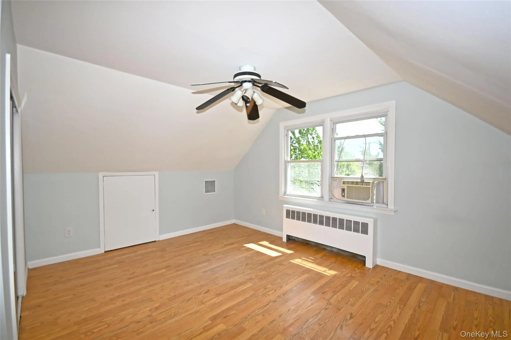 Bonus room with radiator heating unit, light wood finished floors, baseboards, ceiling fan, and cooling unit Bonus room with radiator heating unit, light wood finished floors, baseboards, ceiling fan, and cooling unit
