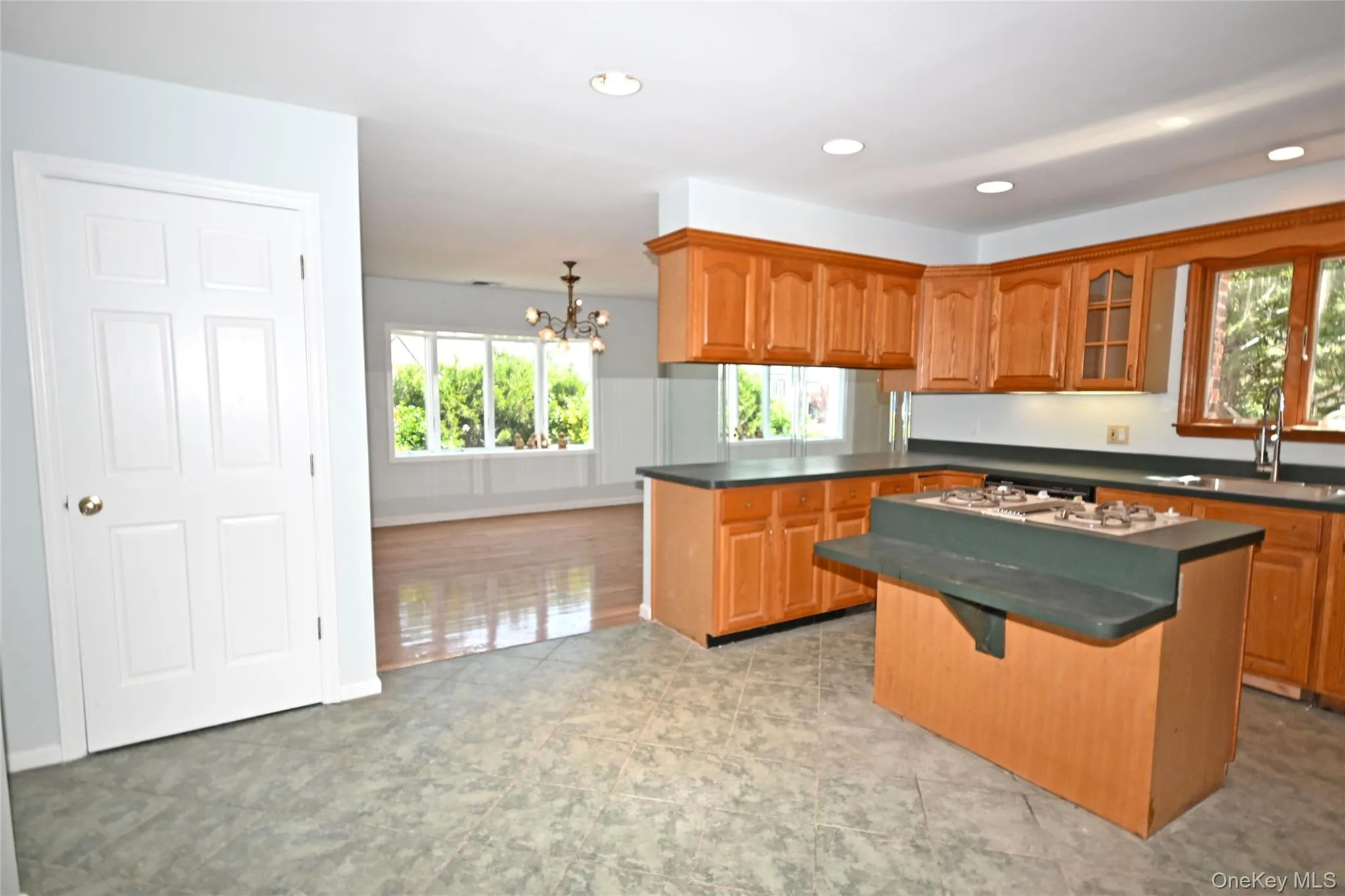 Kitchen with a sink, brown cabinets, a chandelier, a peninsula, and recessed lighting Kitchen with a sink, brown cabinets, a chandelier, a peninsula, and recessed lighting