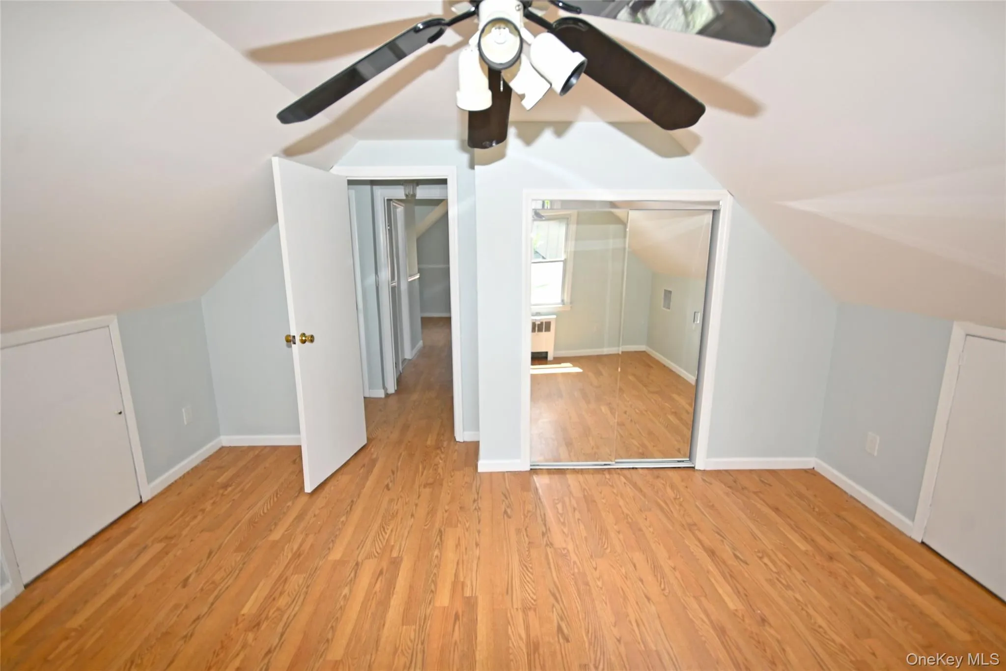 Additional living space with light wood finished floors, vaulted ceiling, baseboards, and radiator Additional living space with light wood finished floors, vaulted ceiling, baseboards, and radiator