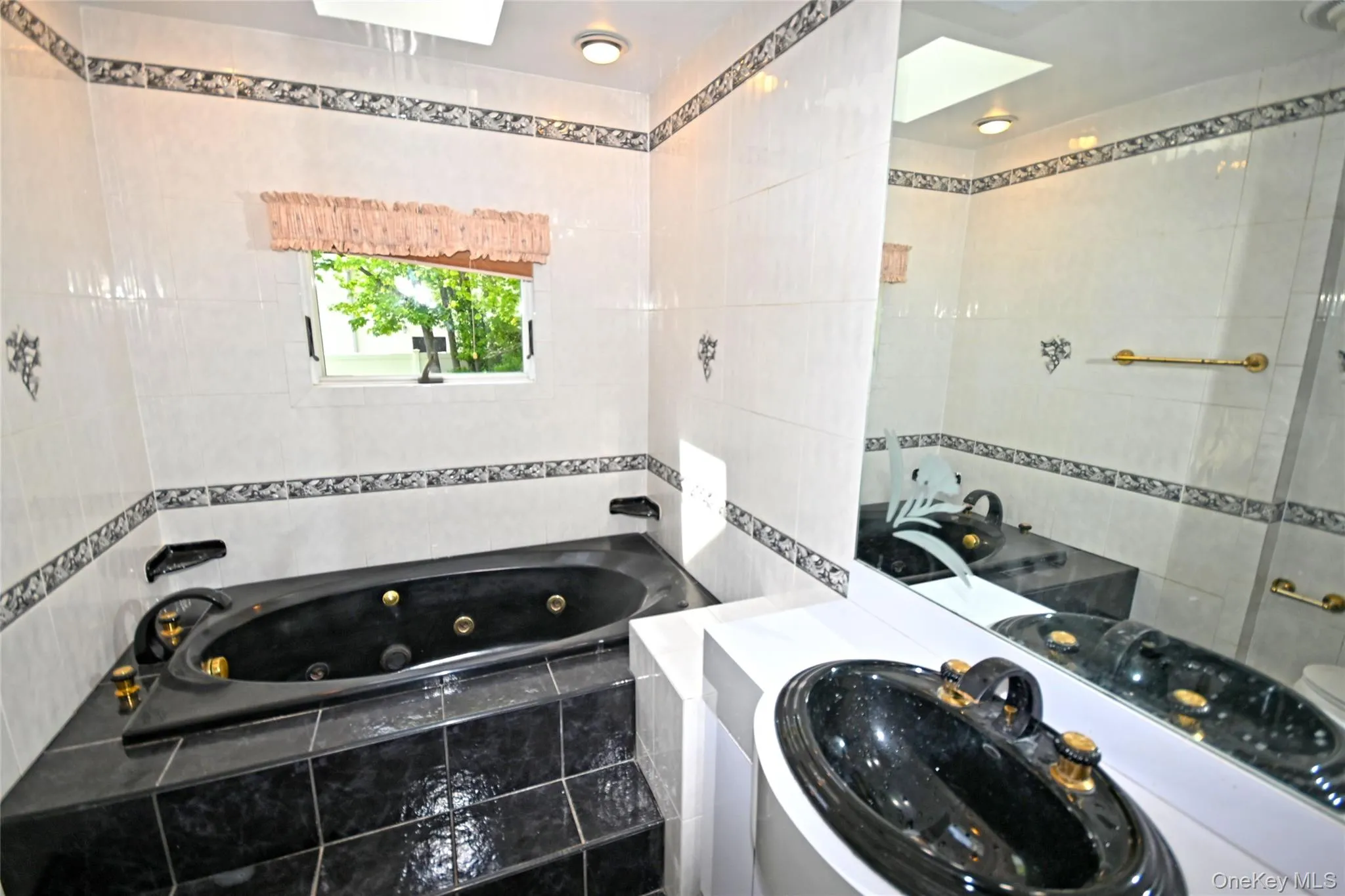 Bathroom with tile walls, a whirlpool tub, and vanity Bathroom with tile walls, a whirlpool tub, and vanity