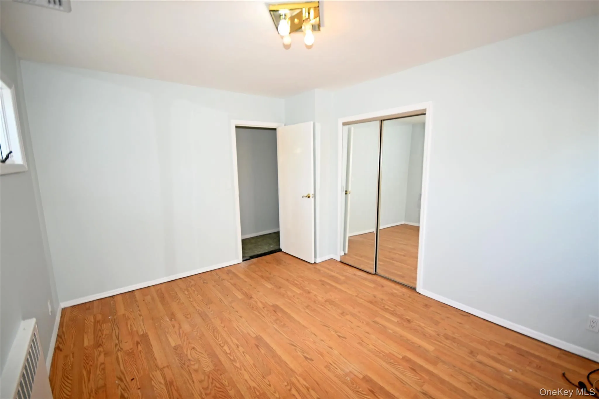 Unfurnished bedroom featuring wood finished floors, a closet, and baseboards Unfurnished bedroom featuring wood finished floors, a closet, and baseboards