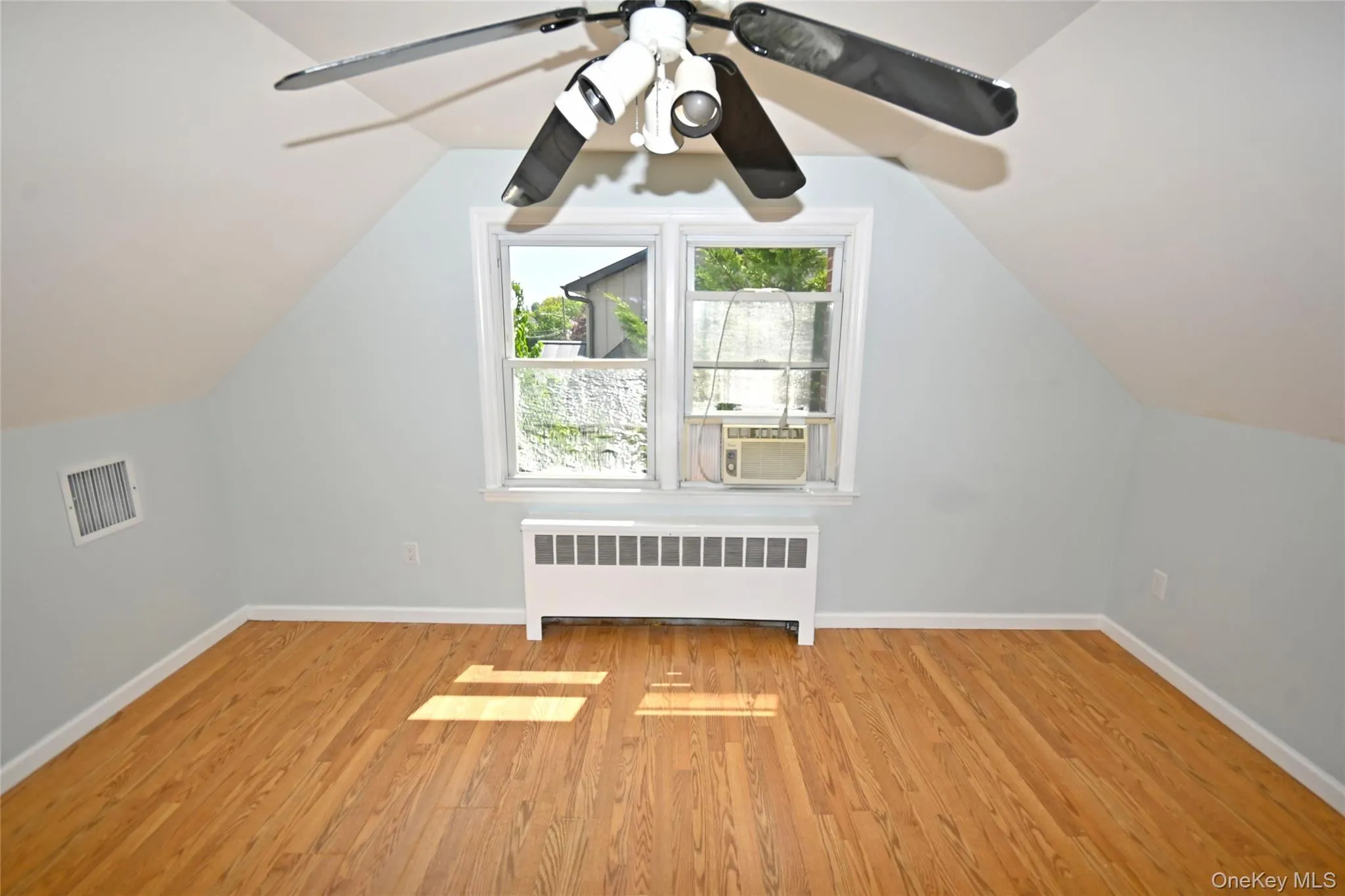 Bonus room with radiator heating unit, wood finished floors, baseboards, and vaulted ceiling Bonus room with radiator heating unit, wood finished floors, baseboards, and vaulted ceiling