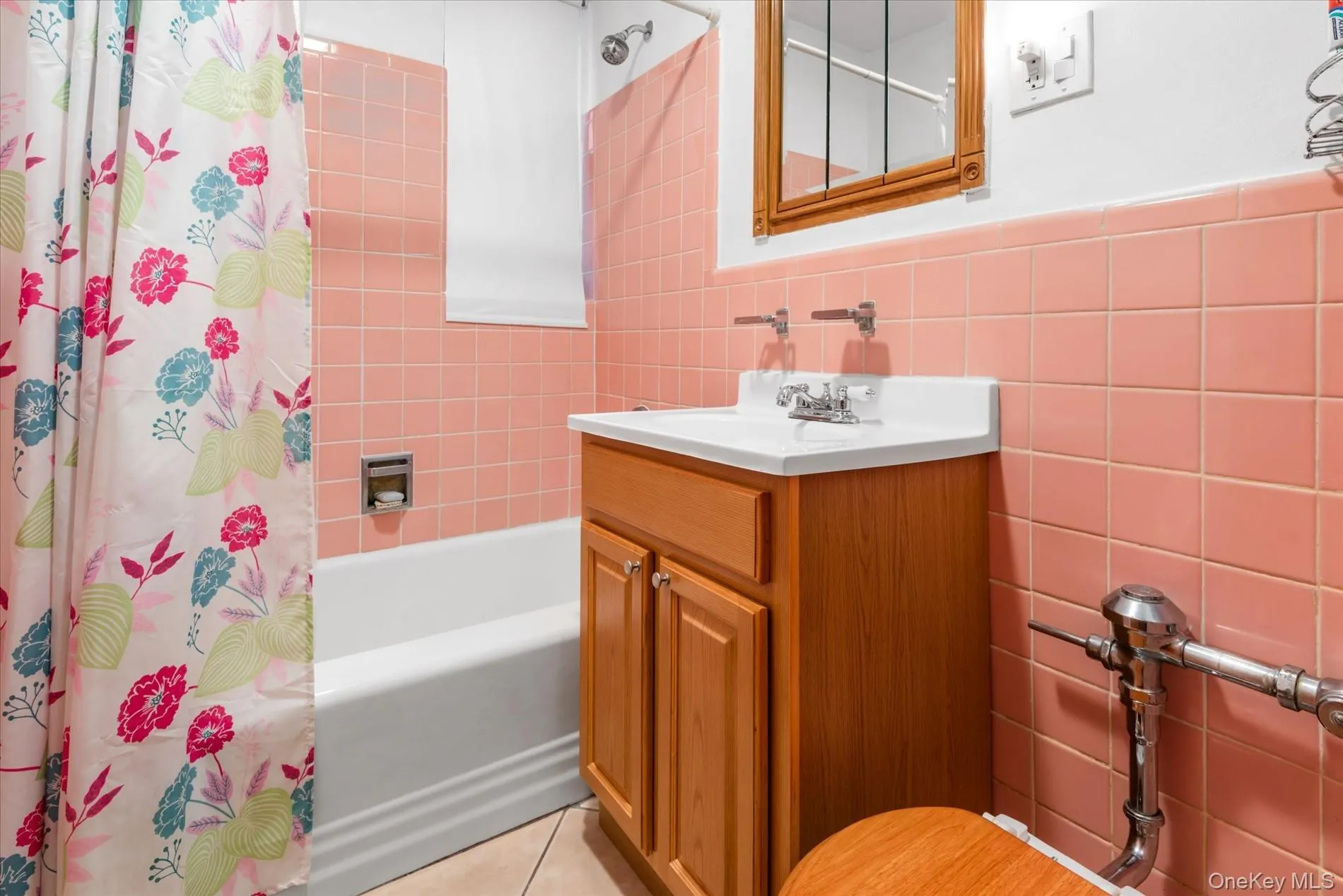 Full bath featuring tile walls, shower / bath combo with shower curtain, vanity, and tile patterned flooring Full bath featuring tile walls, shower / bath combo with shower curtain, vanity, and tile patterned flooring