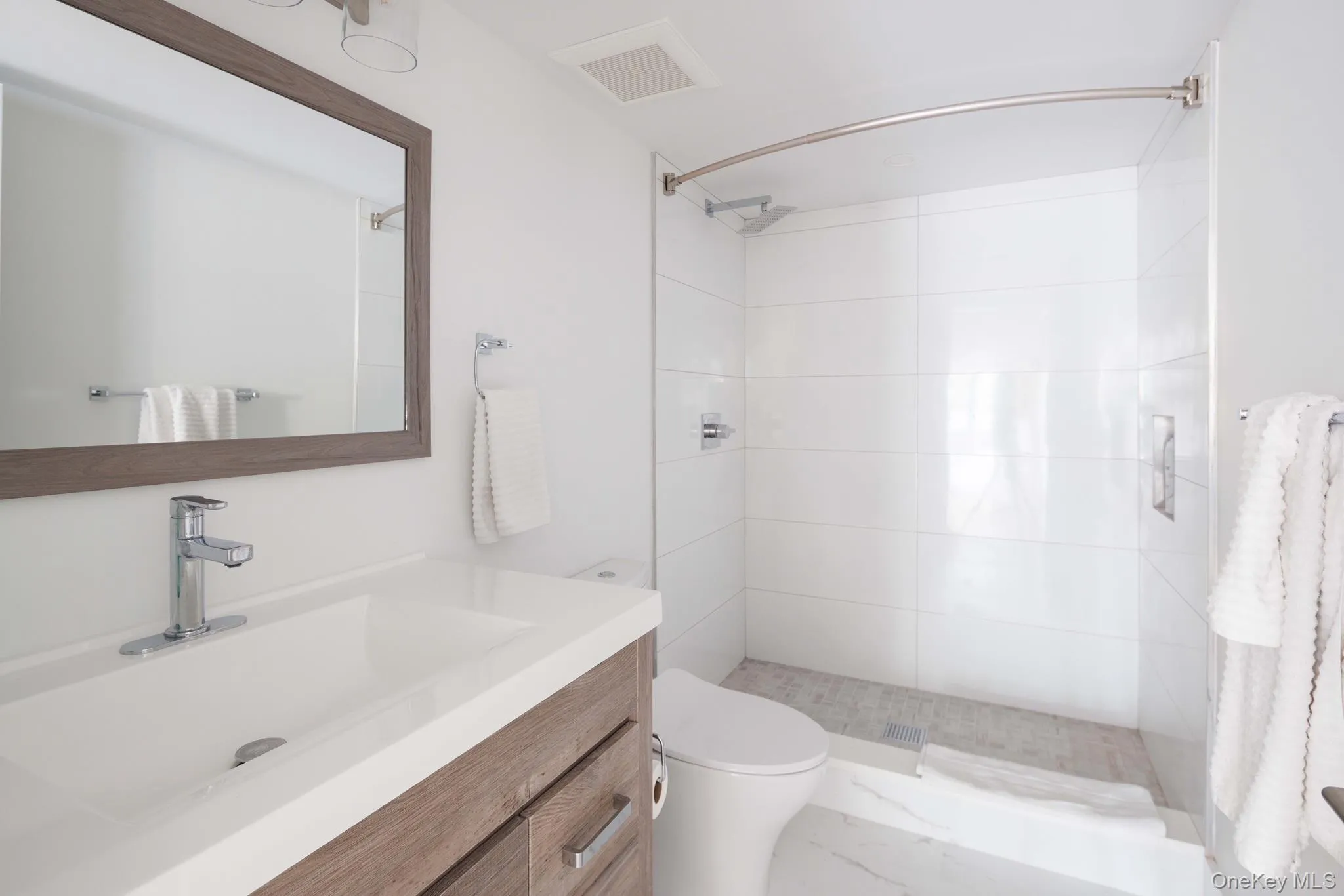 Bathroom with tiled shower, toilet, and vanity Bathroom with tiled shower, toilet, and vanity