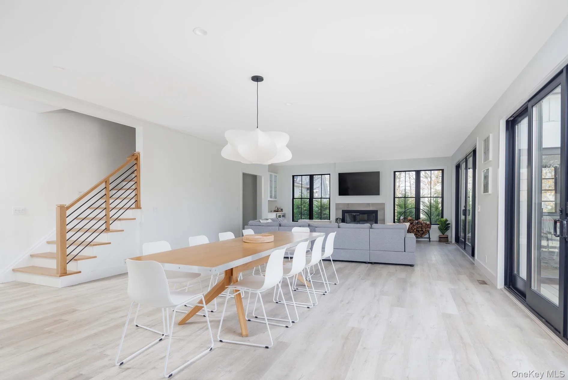 Dining space with light wood-style flooring, a glass covered fireplace, stairs, and baseboards Dining space with light wood-style flooring, a glass covered fireplace, stairs, and baseboards