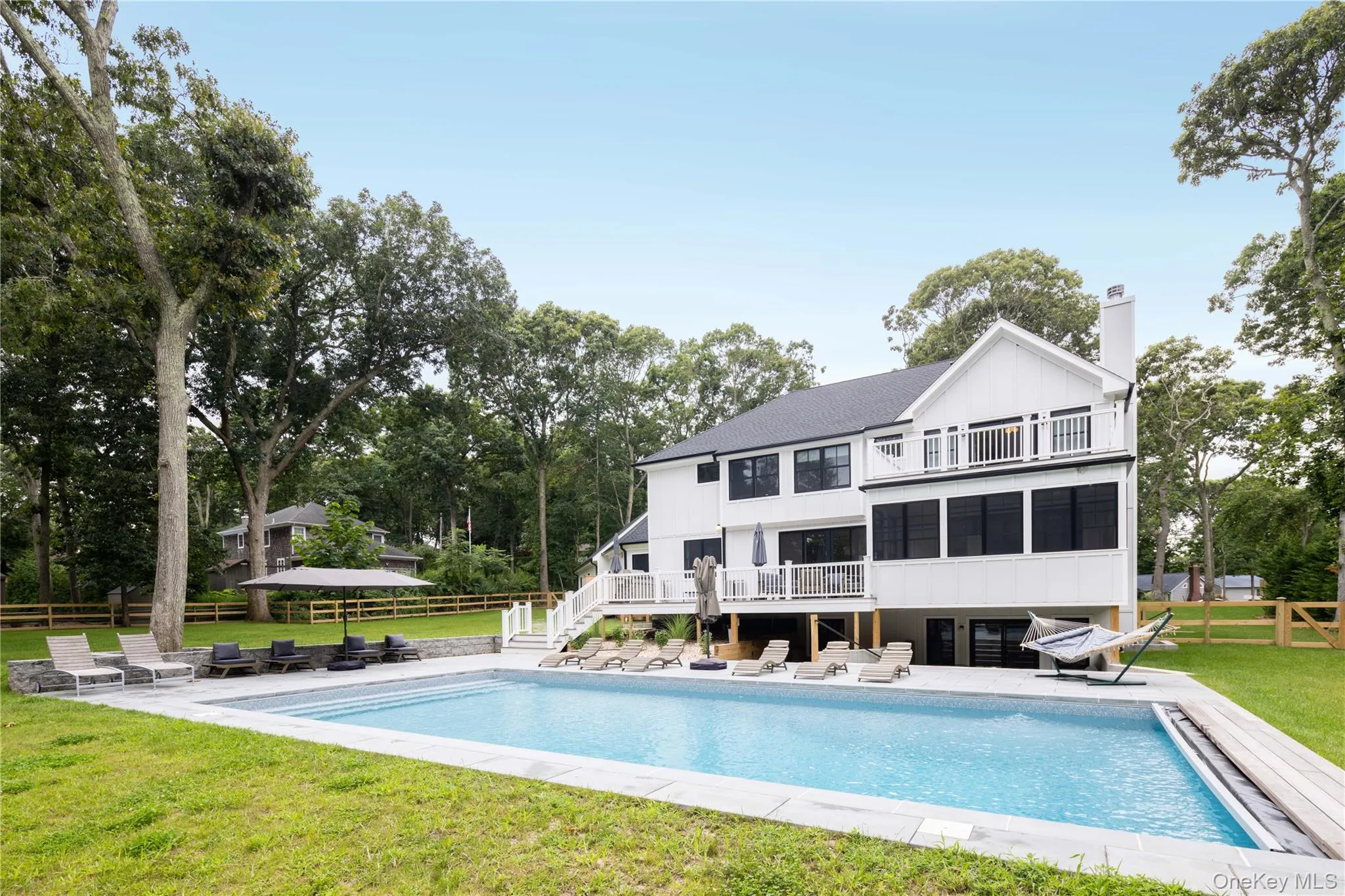 Rear view of house with a balcony, a patio, an outdoor pool, and a chimney Rear view of house with a balcony, a patio, an outdoor pool, and a chimney