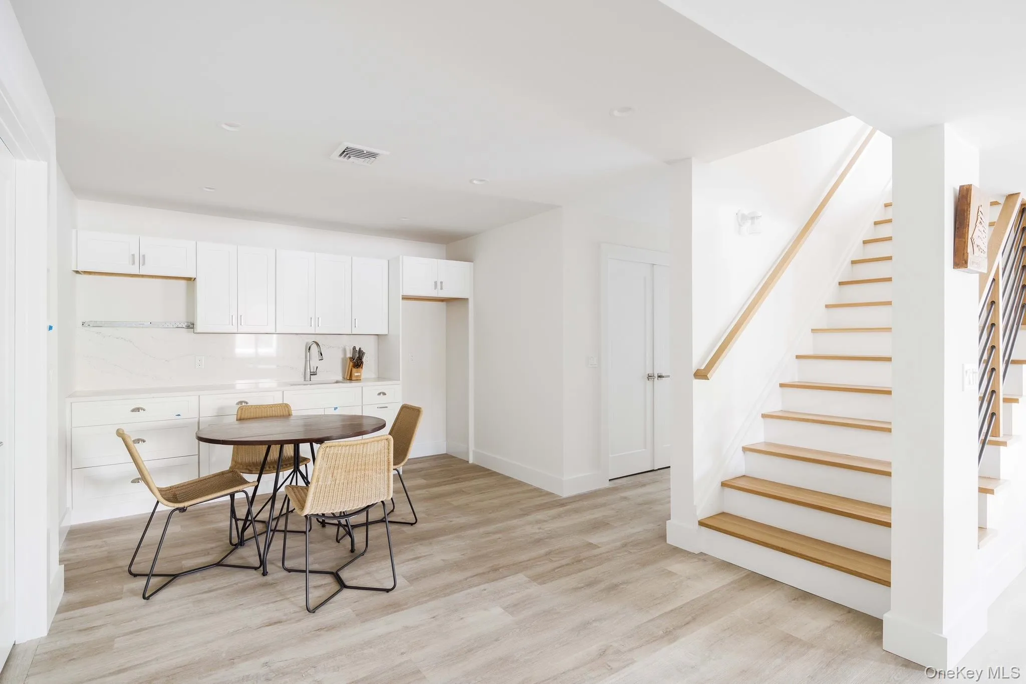Dining space featuring light wood-style flooring, stairs, and baseboards Dining space featuring light wood-style flooring, stairs, and baseboards