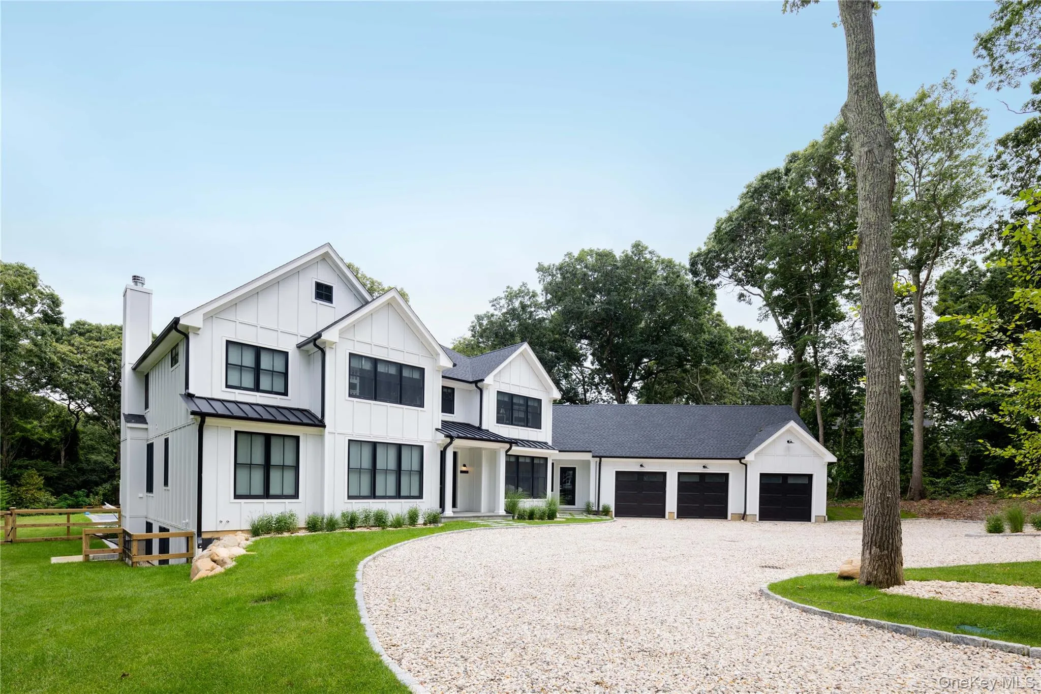 Modern farmhouse with gravel driveway, board and batten siding, an attached garage, a standing seam roof, and a chimney Modern farmhouse with gravel driveway, board and batten siding, an attached garage, a standing seam roof, and a chimney