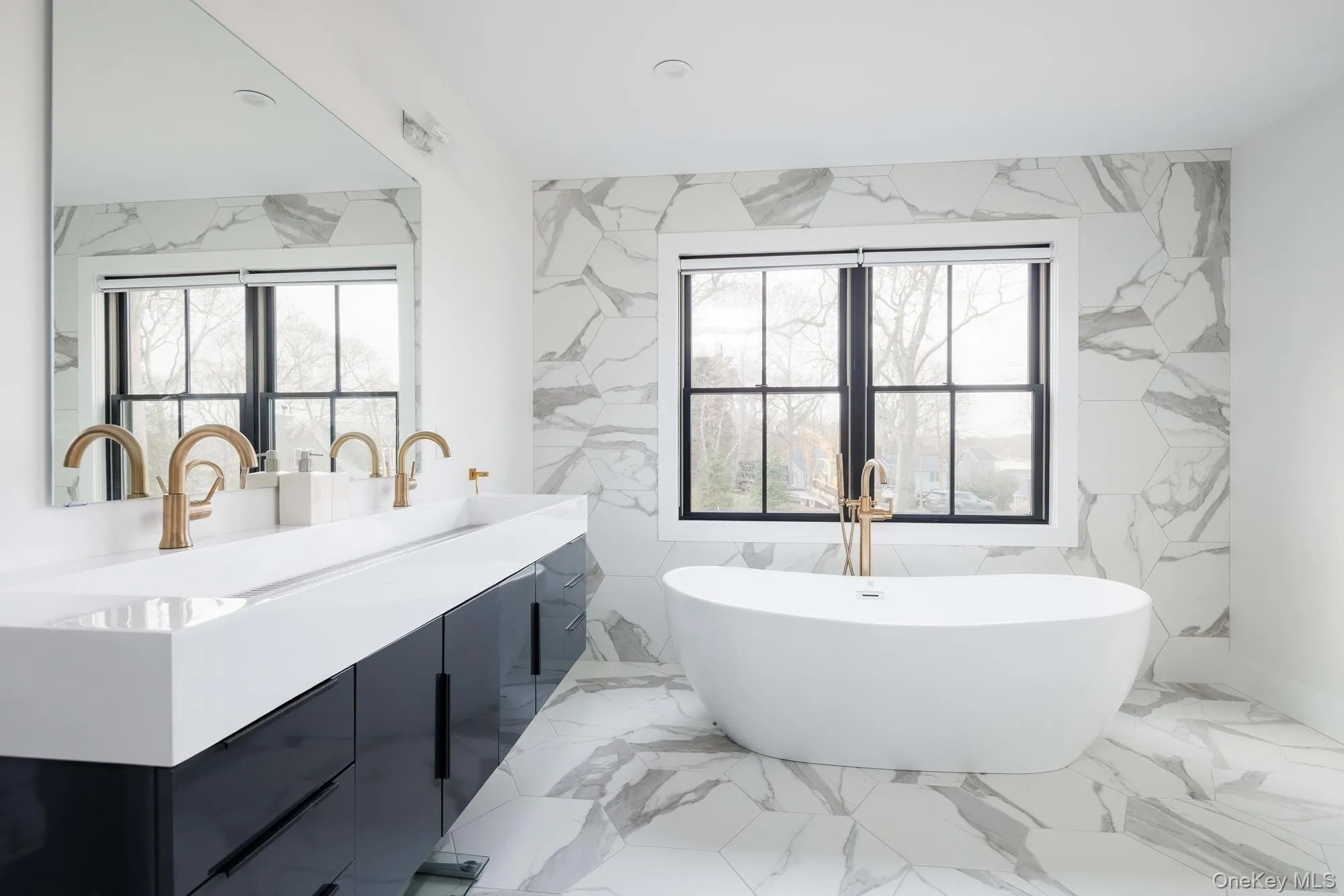 Bathroom with a soaking tub, double vanity, marble finish floors, and tile walls Bathroom with a soaking tub, double vanity, marble finish floors, and tile walls