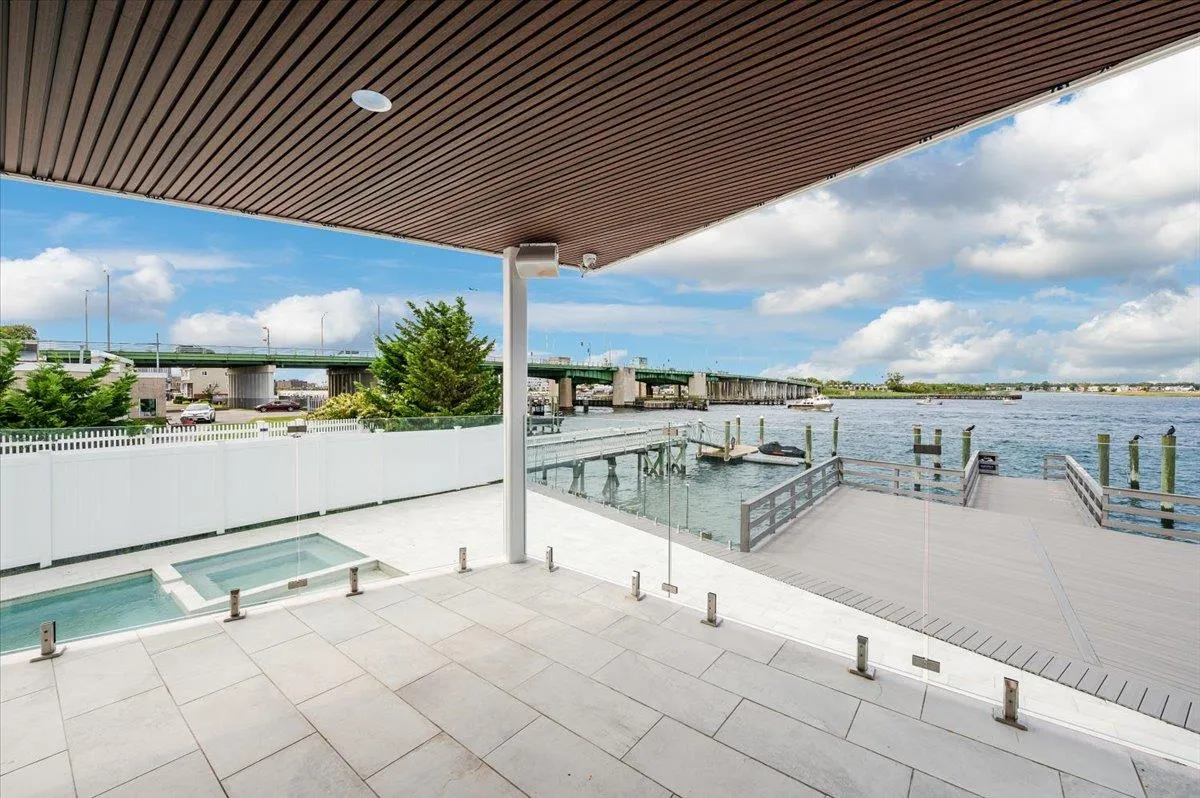 View of swimming pool featuring a dock, a water view, fence, and a pool with connected hot tub View of swimming pool featuring a dock, a water view, fence, and a pool with connected hot tub