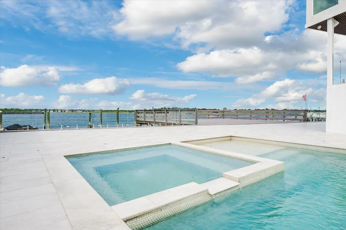 View of pool with fence and a pool with connected hot tub View of pool with fence and a pool with connected hot tub