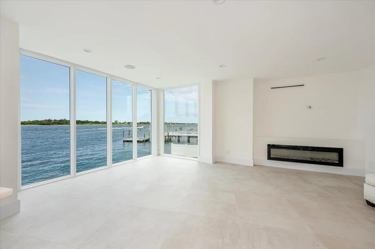 Unfurnished living room featuring a wall of windows, a glass covered fireplace, and a water view Unfurnished living room featuring a wall of windows, a glass covered fireplace, and a water view
