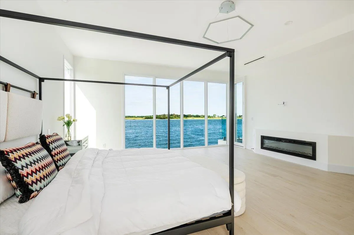 Bedroom with wood finished floors, a water view, access to outside, and a glass covered fireplace Bedroom with wood finished floors, a water view, access to outside, and a glass covered fireplace