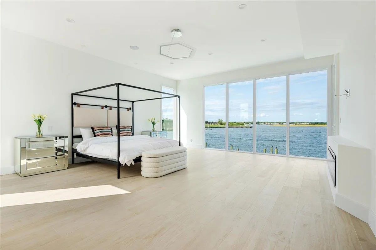 Bedroom featuring access to outside, wood finished floors, baseboards, and a water view Bedroom featuring access to outside, wood finished floors, baseboards, and a water view