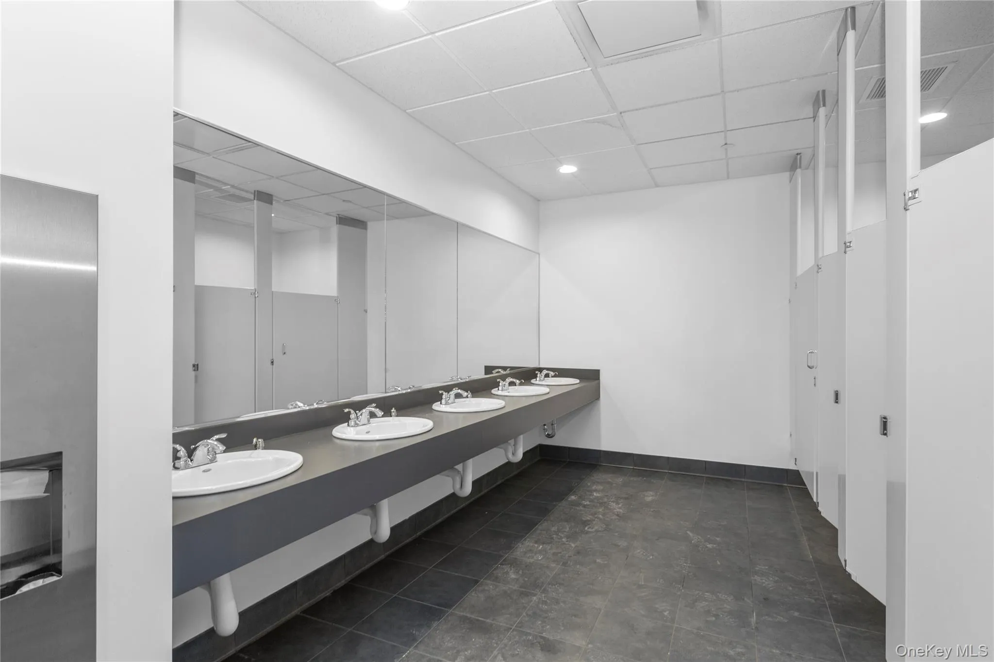 Bathroom featuring a paneled ceiling, baseboards, and double vanity Bathroom featuring a paneled ceiling, baseboards, and double vanity