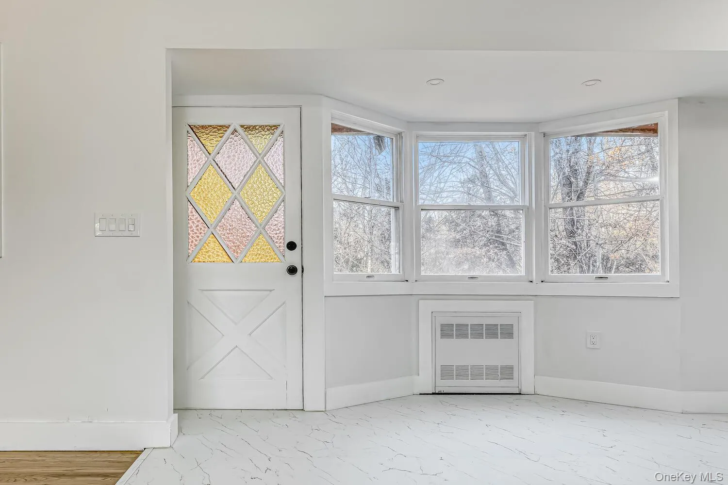 Foyer entrance featuring radiator, marble finish floors, and baseboards Foyer entrance featuring radiator, marble finish floors, and baseboards