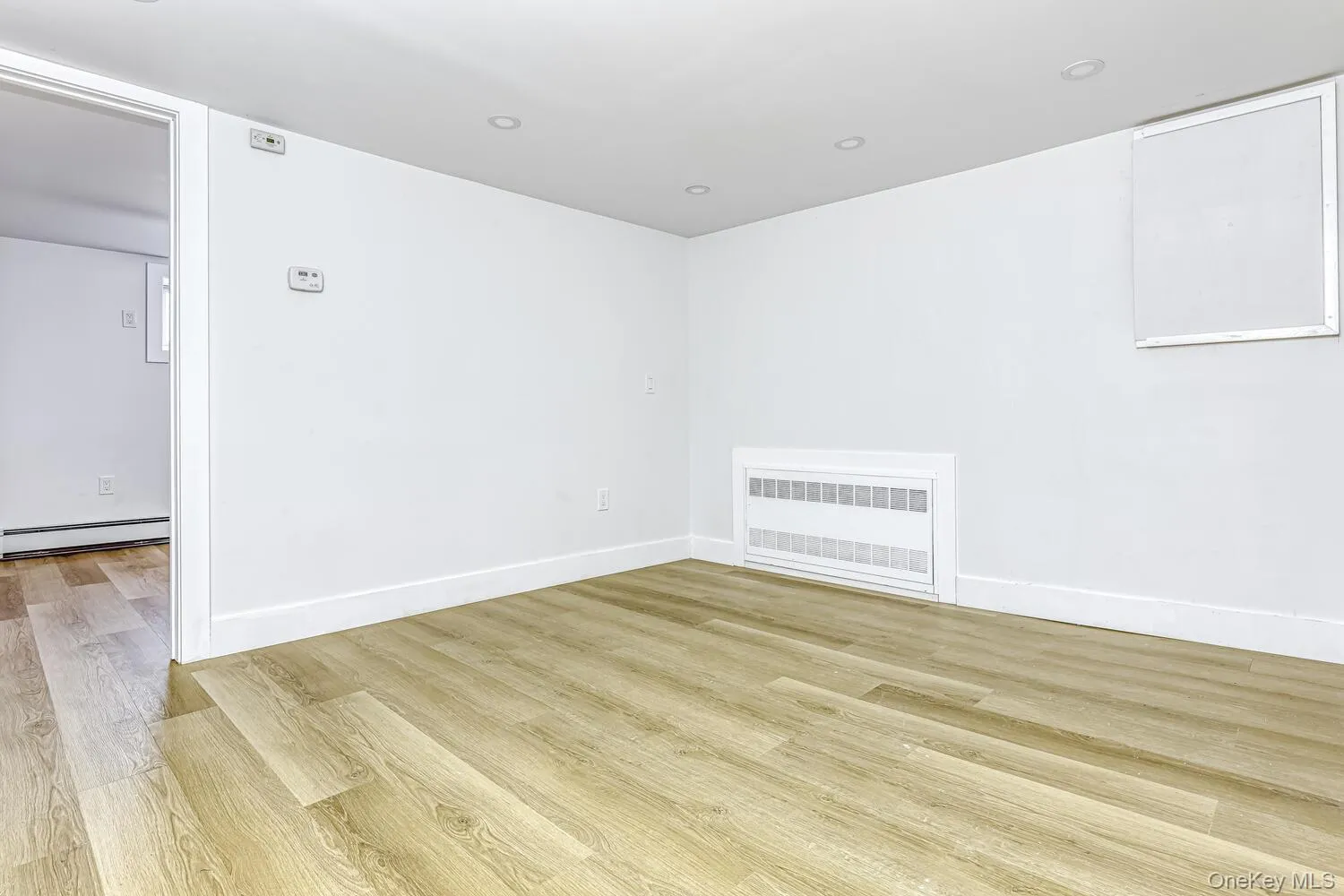 Spare room with a baseboard radiator, wood finished floors, radiator heating unit, and baseboards Spare room with a baseboard radiator, wood finished floors, radiator heating unit, and baseboards