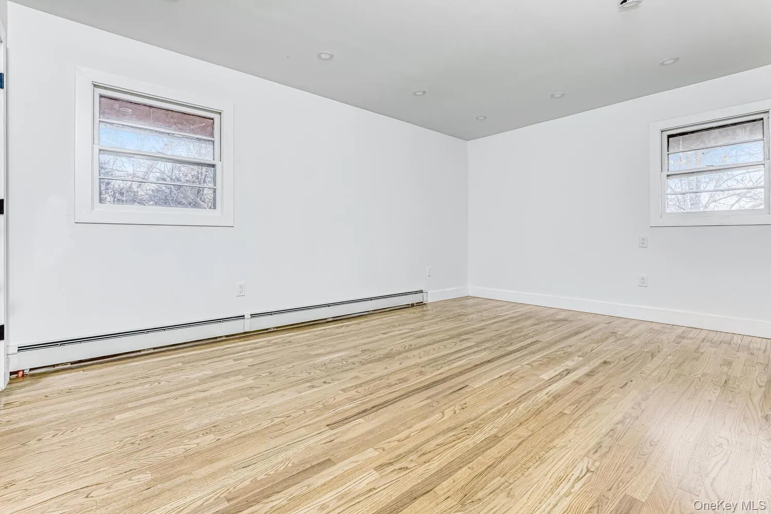 Unfurnished room with a baseboard heating unit, wood finished floors, and baseboards Unfurnished room with a baseboard heating unit, wood finished floors, and baseboards