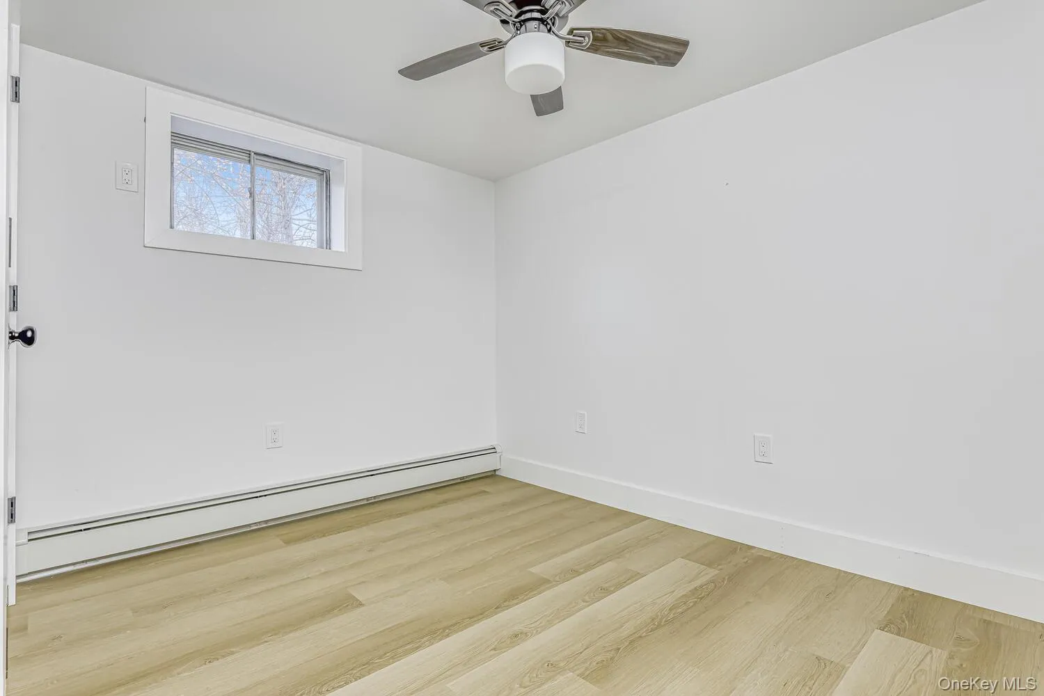 Spare room with a baseboard radiator, wood finished floors, baseboards, and ceiling fan Spare room with a baseboard radiator, wood finished floors, baseboards, and ceiling fan