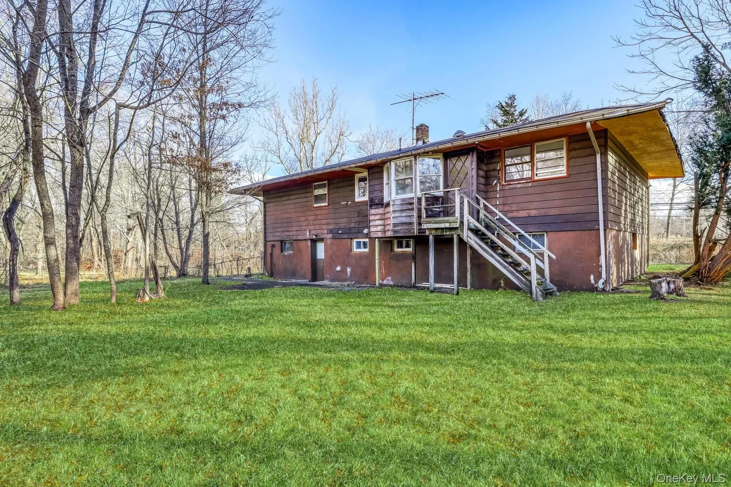 Back of property featuring a chimney, a yard, stairway, and a deck Back of property featuring a chimney, a yard, stairway, and a deck