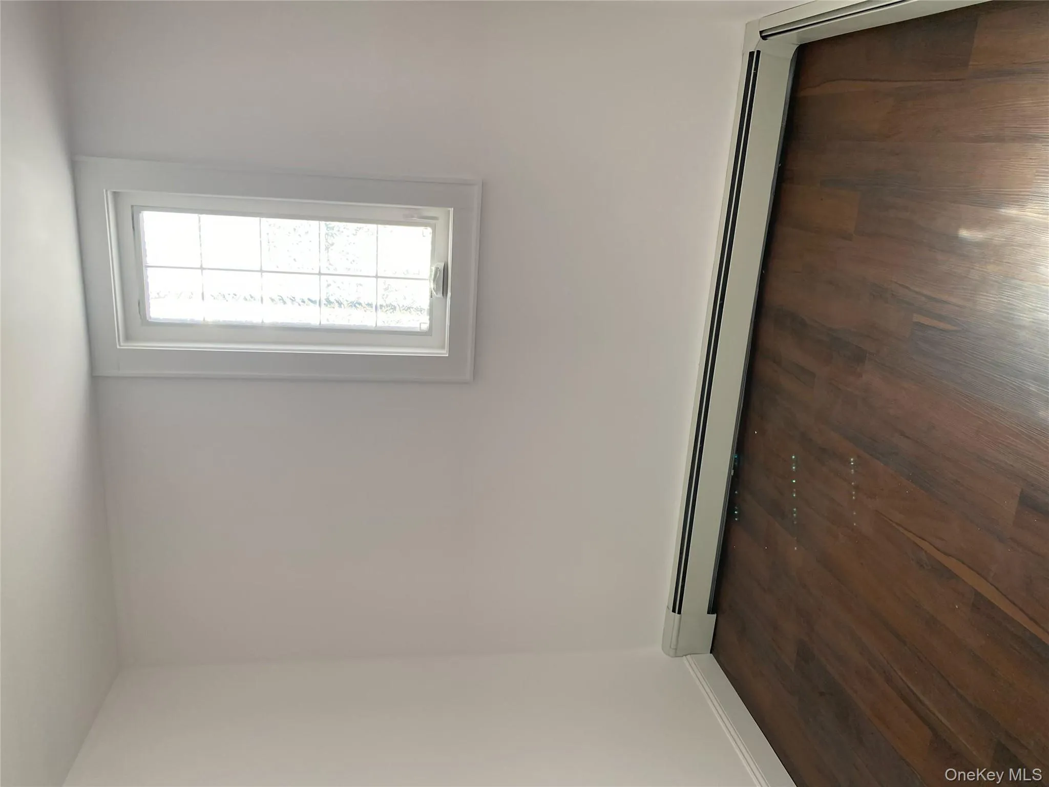 Empty room with baseboard heating, dark wood-style floors, and baseboards Empty room with baseboard heating, dark wood-style floors, and baseboards