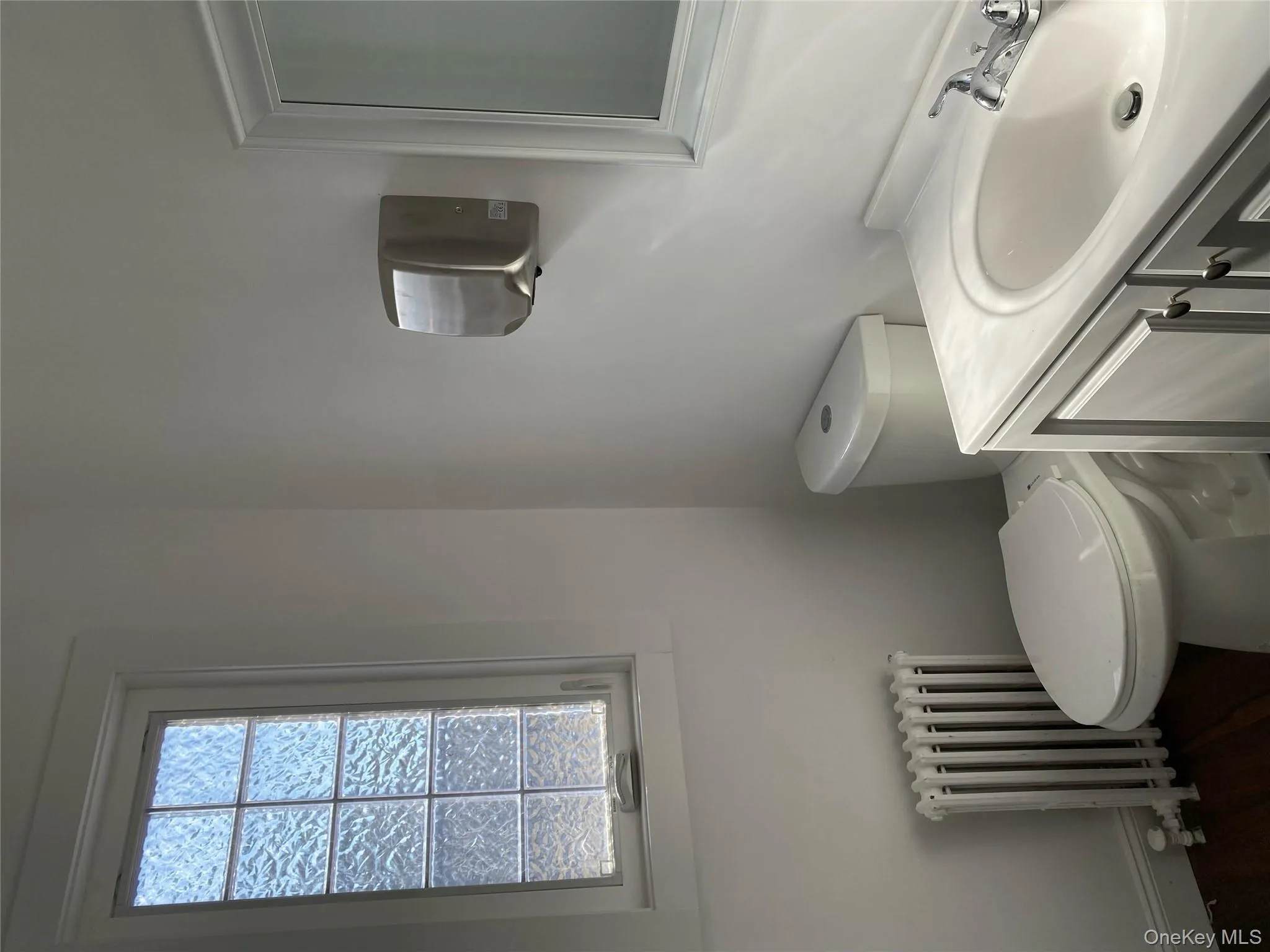 Half bathroom with radiator heating unit, toilet, vanity, and wood finished floors Half bathroom with radiator heating unit, toilet, vanity, and wood finished floors