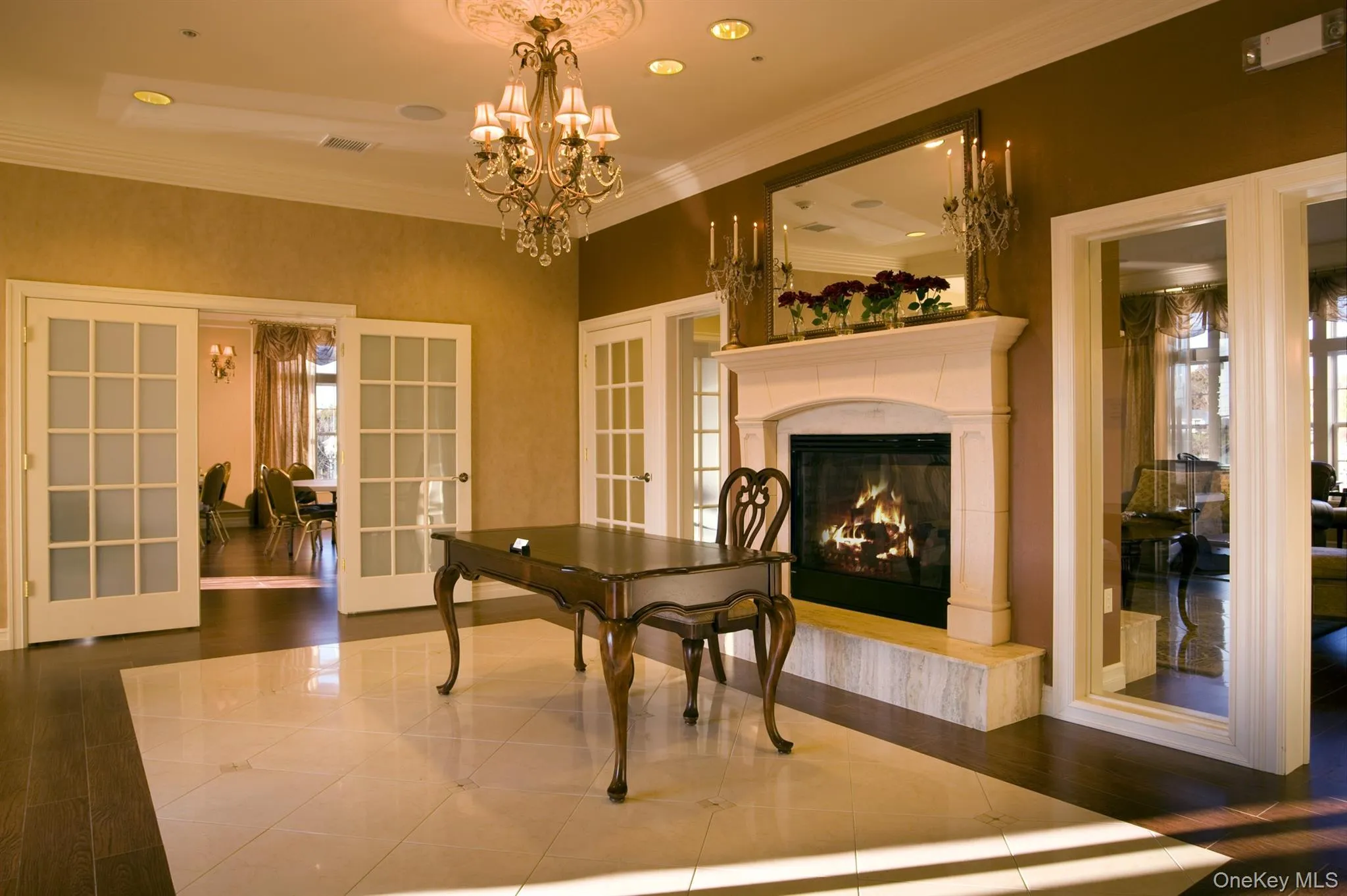Dining room with french doors, ornamental molding, a chandelier, a high end fireplace, and recessed lighting Dining room with french doors, ornamental molding, a chandelier, a high end fireplace, and recessed lighting