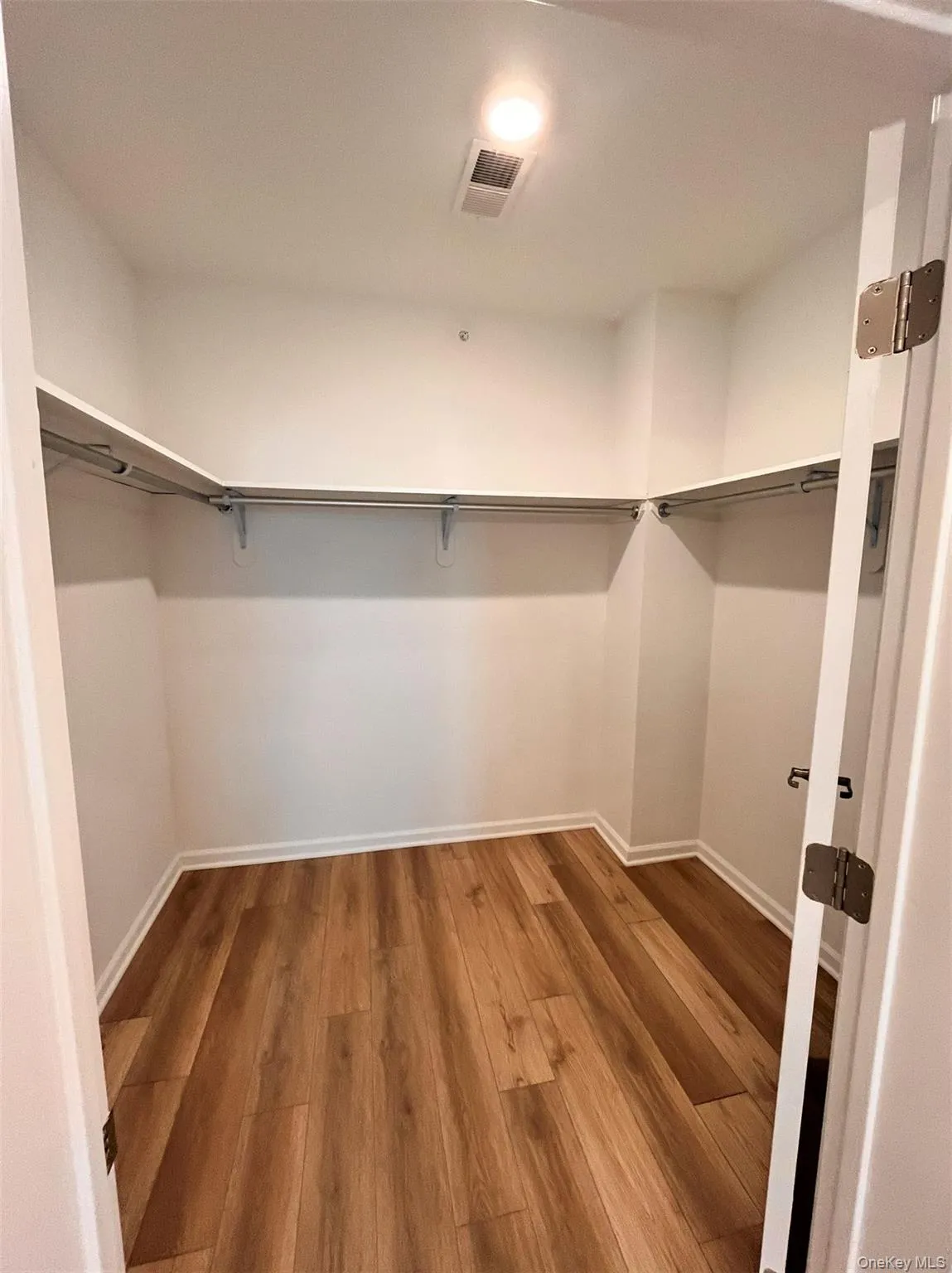Primary Walk in closet featuring wood finished floors Primary Walk in closet featuring wood finished floors