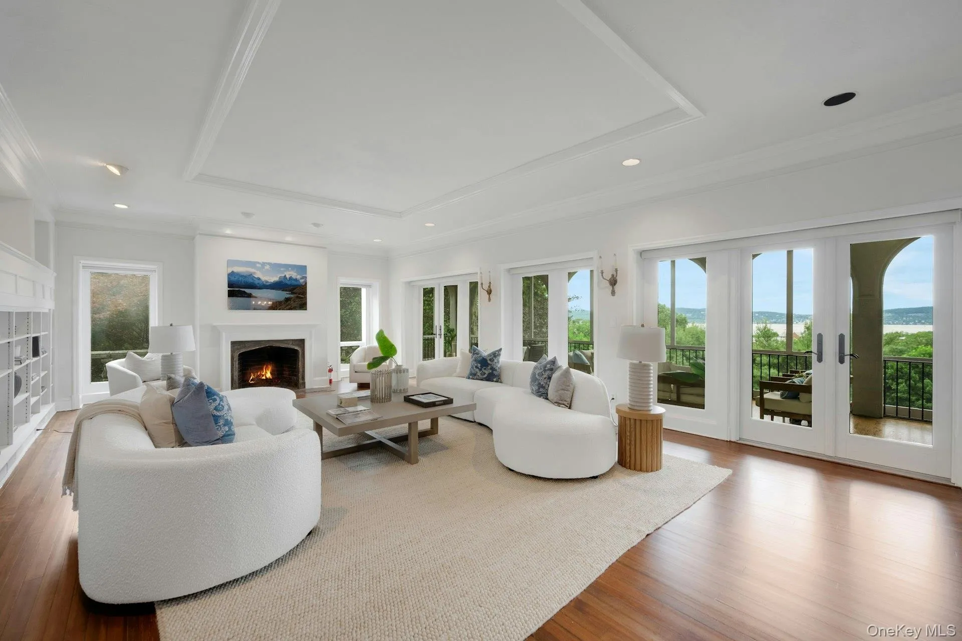 Living area featuring a warm lit fireplace, a tray ceiling, healthy amount of natural light, french doors, and ornamental molding w/Hudson River views. Living area featuring a warm lit fireplace, a tray ceiling, healthy amount of natural light, french doors, and ornamental molding w/Hudson River views.