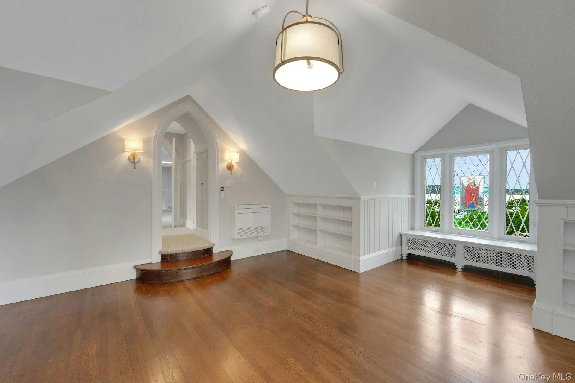 Additional (top level) living space with built in features, radiator, wood finished floors, and lofted ceiling. Additional bedroom Additional (top level) living space with built in features, radiator, wood finished floors, and lofted ceiling. Additional bedroom