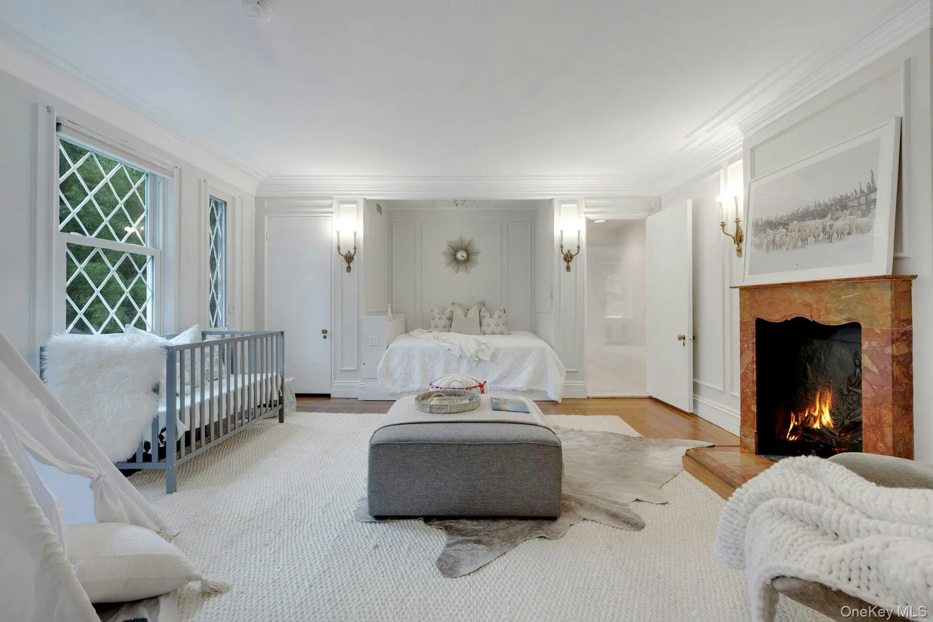 Nursery option/Bedroom with ornamental molding, a warm lit fireplace, and light wood-type flooring Nursery option/Bedroom with ornamental molding, a warm lit fireplace, and light wood-type flooring