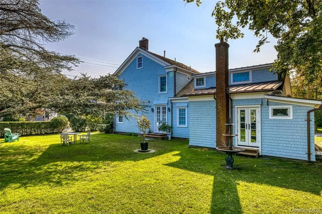 Rear view of house with french doors, a standing seam roof, a lawn, and a chimney Rear view of house with french doors, a standing seam roof, a lawn, and a chimney