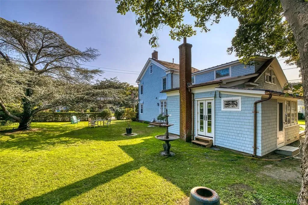 Rear view of house with entry steps, a lawn, and french doors Rear view of house with entry steps, a lawn, and french doors