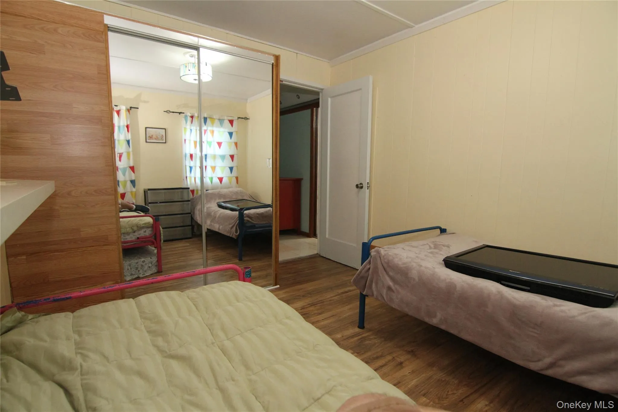 Bedroom with wood finished floors, crown molding, and a closet Bedroom with wood finished floors, crown molding, and a closet