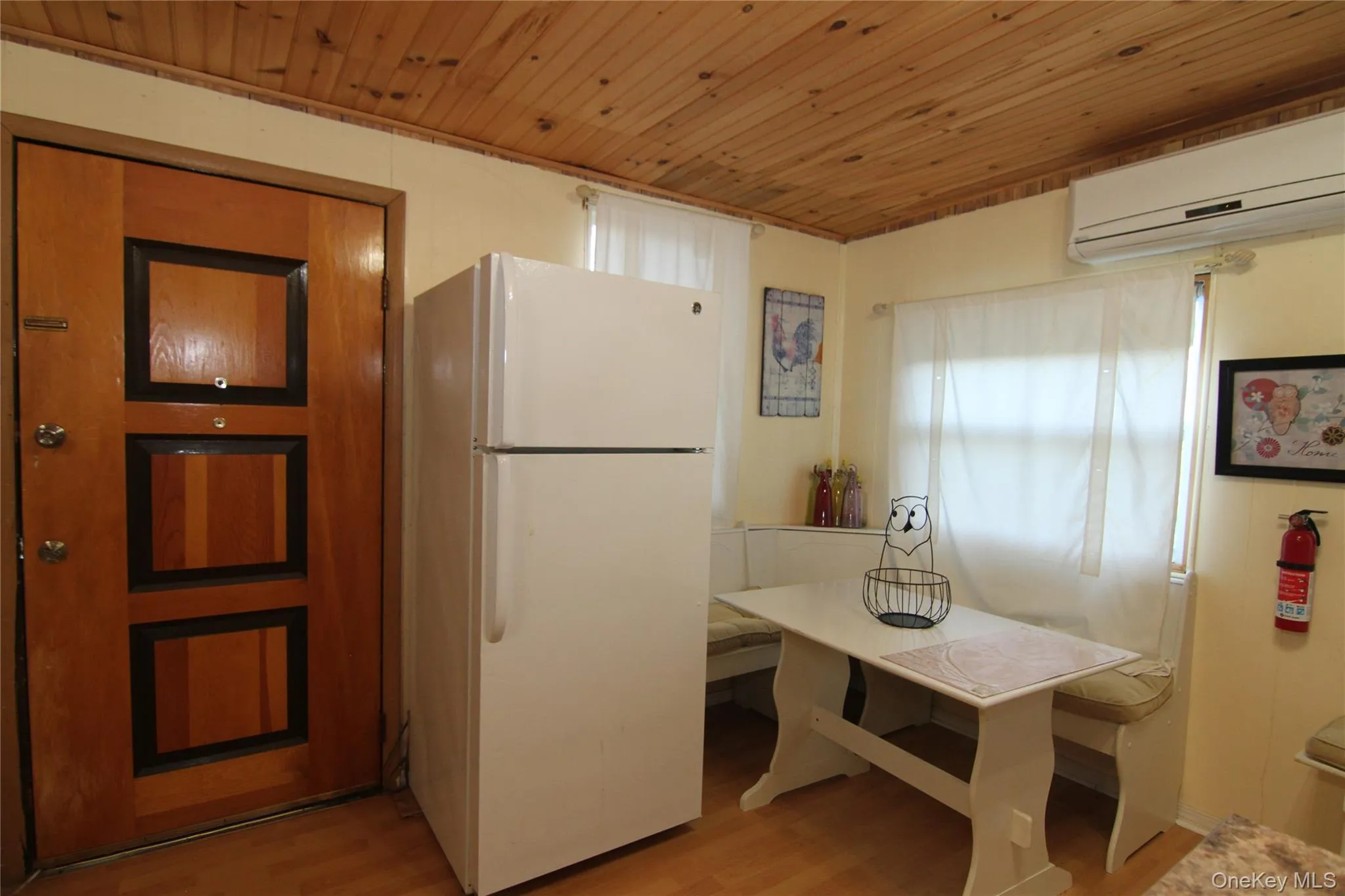 Kitchen featuring freestanding refrigerator, light wood-style floors, an AC wall unit, and wooden ceiling Kitchen featuring freestanding refrigerator, light wood-style floors, an AC wall unit, and wooden ceiling
