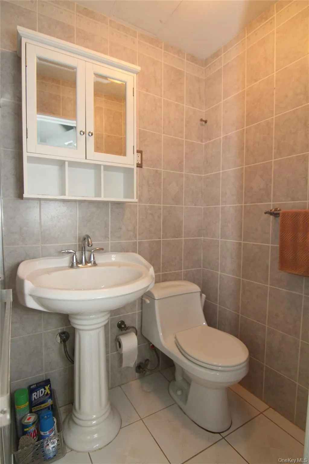 Bathroom with tile walls, toilet, and tile patterned flooring Bathroom with tile walls, toilet, and tile patterned flooring