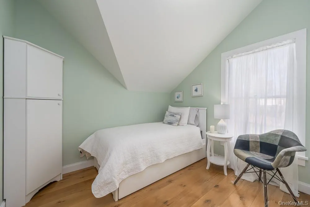 Bedroom featuring vaulted ceiling, wood finished floors, and baseboards Bedroom featuring vaulted ceiling, wood finished floors, and baseboards