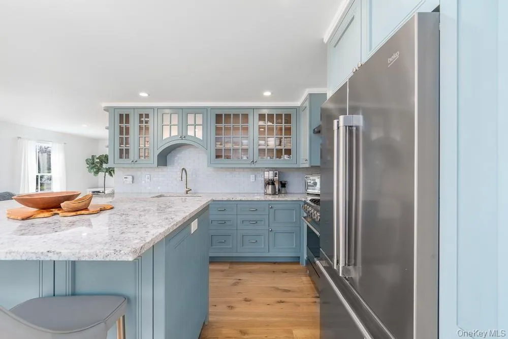 Kitchen featuring high end refrigerator, a sink, light wood finished floors, a kitchen bar, and recessed lighting Kitchen featuring high end refrigerator, a sink, light wood finished floors, a kitchen bar, and recessed lighting