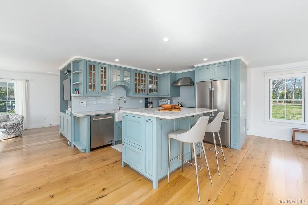 Kitchen featuring appliances with stainless steel finishes, tasteful backsplash, a breakfast bar, a center island, and light stone counters Kitchen featuring appliances with stainless steel finishes, tasteful backsplash, a breakfast bar, a center island, and light stone counters