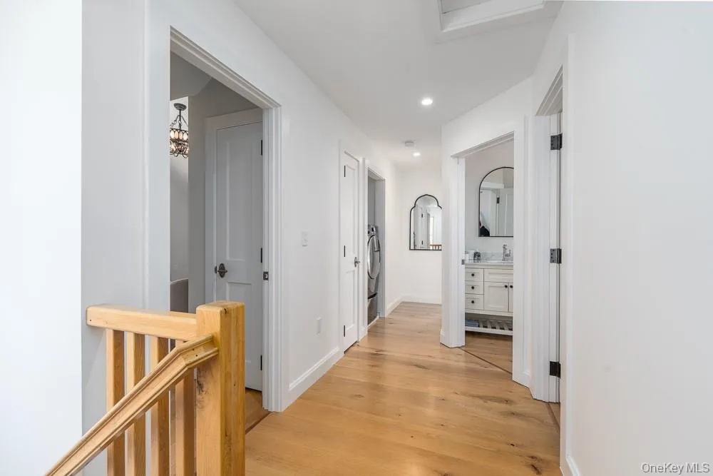 Hallway with light wood-type flooring, recessed lighting, a sink, and baseboards Hallway with light wood-type flooring, recessed lighting, a sink, and baseboards