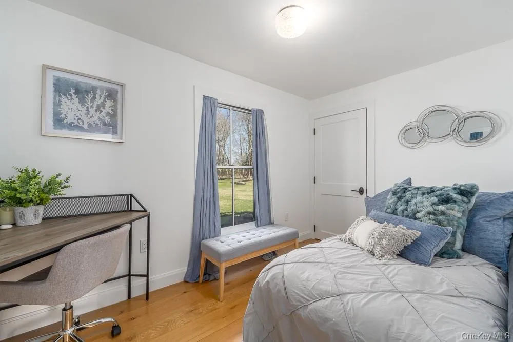 Bedroom with light wood-type flooring, baseboards, and an office area Bedroom with light wood-type flooring, baseboards, and an office area