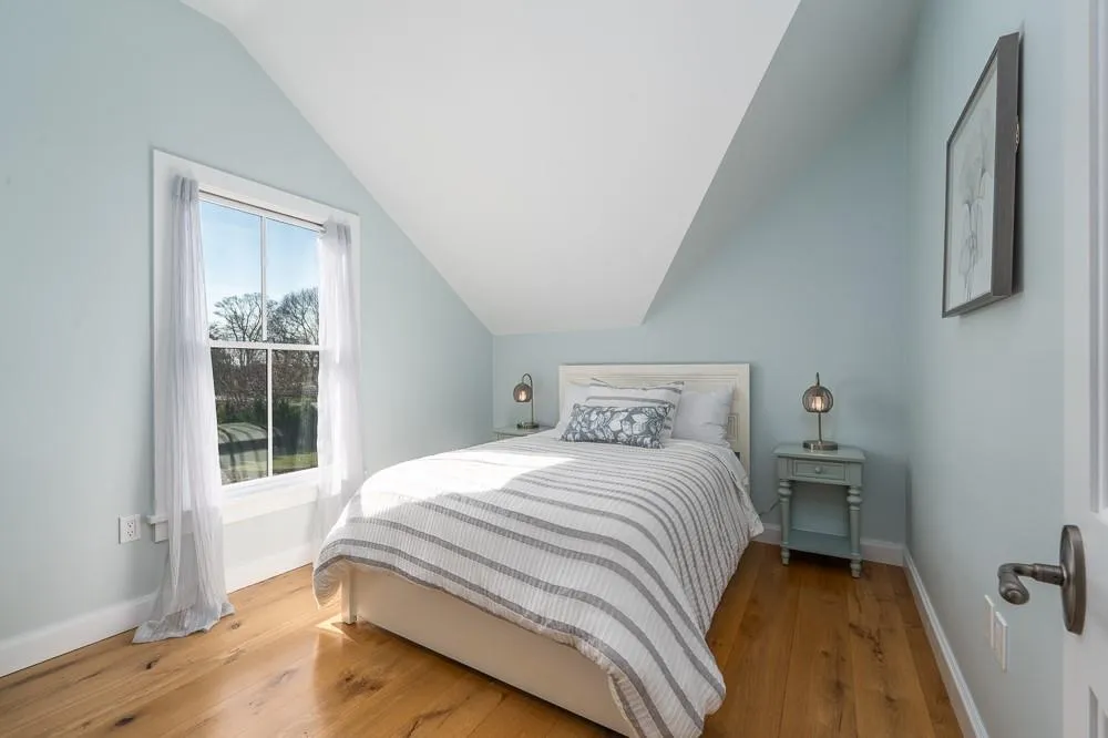 Bedroom featuring vaulted ceiling, baseboards, and hardwood / wood-style floors Bedroom featuring vaulted ceiling, baseboards, and hardwood / wood-style floors