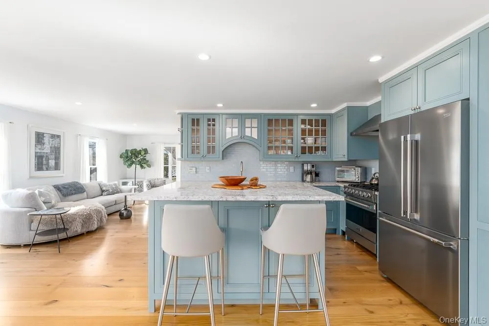 Kitchen with premium appliances, wall chimney exhaust hood, a kitchen breakfast bar, decorative backsplash, and recessed lighting Kitchen with premium appliances, wall chimney exhaust hood, a kitchen breakfast bar, decorative backsplash, and recessed lighting