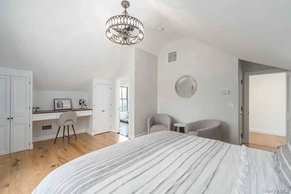 Bedroom with lofted ceiling, light wood-type flooring, and a chandelier Bedroom with lofted ceiling, light wood-type flooring, and a chandelier