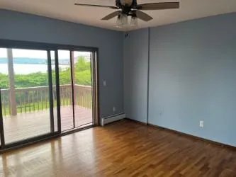 Spare room with a water view, wood finished floors, a ceiling fan, and a baseboard radiator Spare room with a water view, wood finished floors, a ceiling fan, and a baseboard radiator